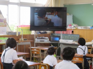 「朝の歌」の時間に，TV放送で子どものがんばっているスライドを見ながら音楽を聴く子どもたち