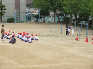 てつぼうあそびで「こうもり」する子どもとじゃんけんをする１年１組の子どもたち