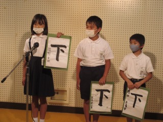 お昼の放送「神亀っ子タイム」で書写の取組を紹介する３年１組の子どもたち