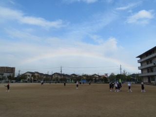 虹の出ている空の下で遊ぶ子どもたち